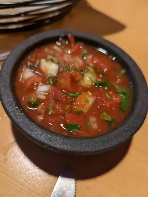 Close-up of chunky red salsa with cilantro in a black stone bowl